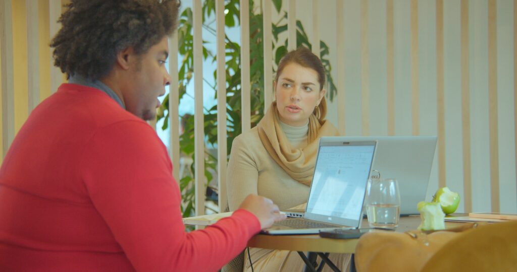 Een man en een vrouw zitten aan een bureau op hun laptops te werken