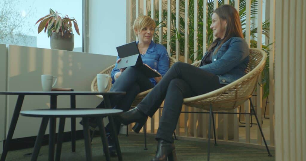 Twee vrouwen zitten in stoelen met laptops op hun schoot